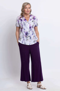 Full front view of a woman in a floral button-up shirt and purple wide-leg pants