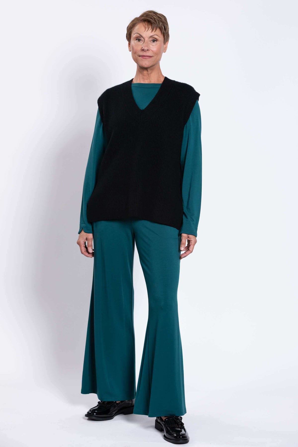 Full front view of woman in oversized black vest and teal outfit