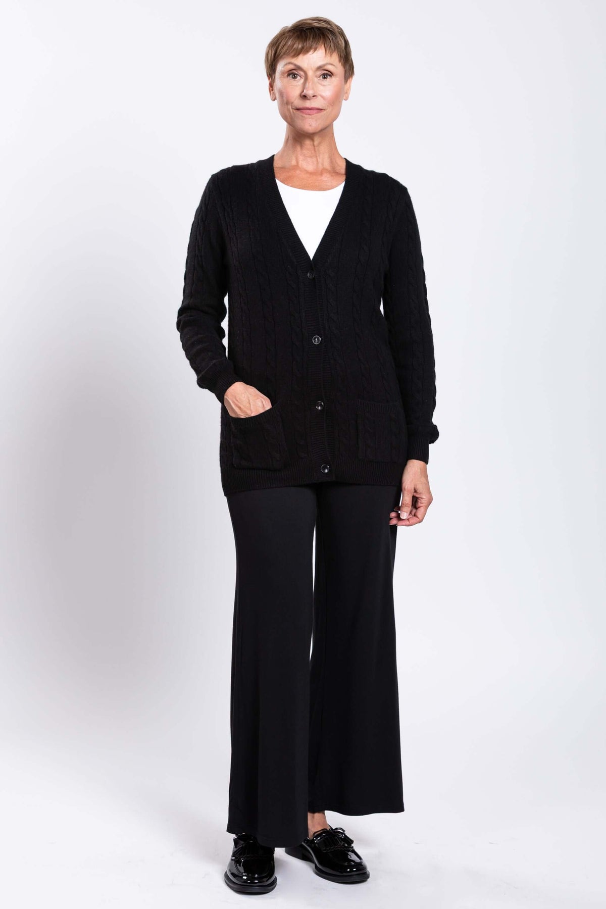 Full length front view of a woman in black cable knit cardigan and wide-leg pants