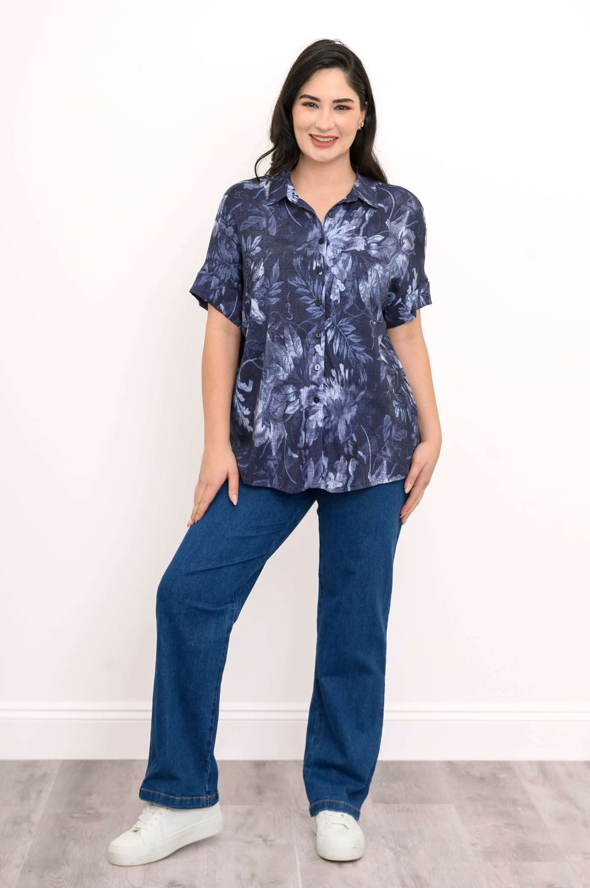 Full length shot of woman in blue floral blouse and jeans, standing and smiling