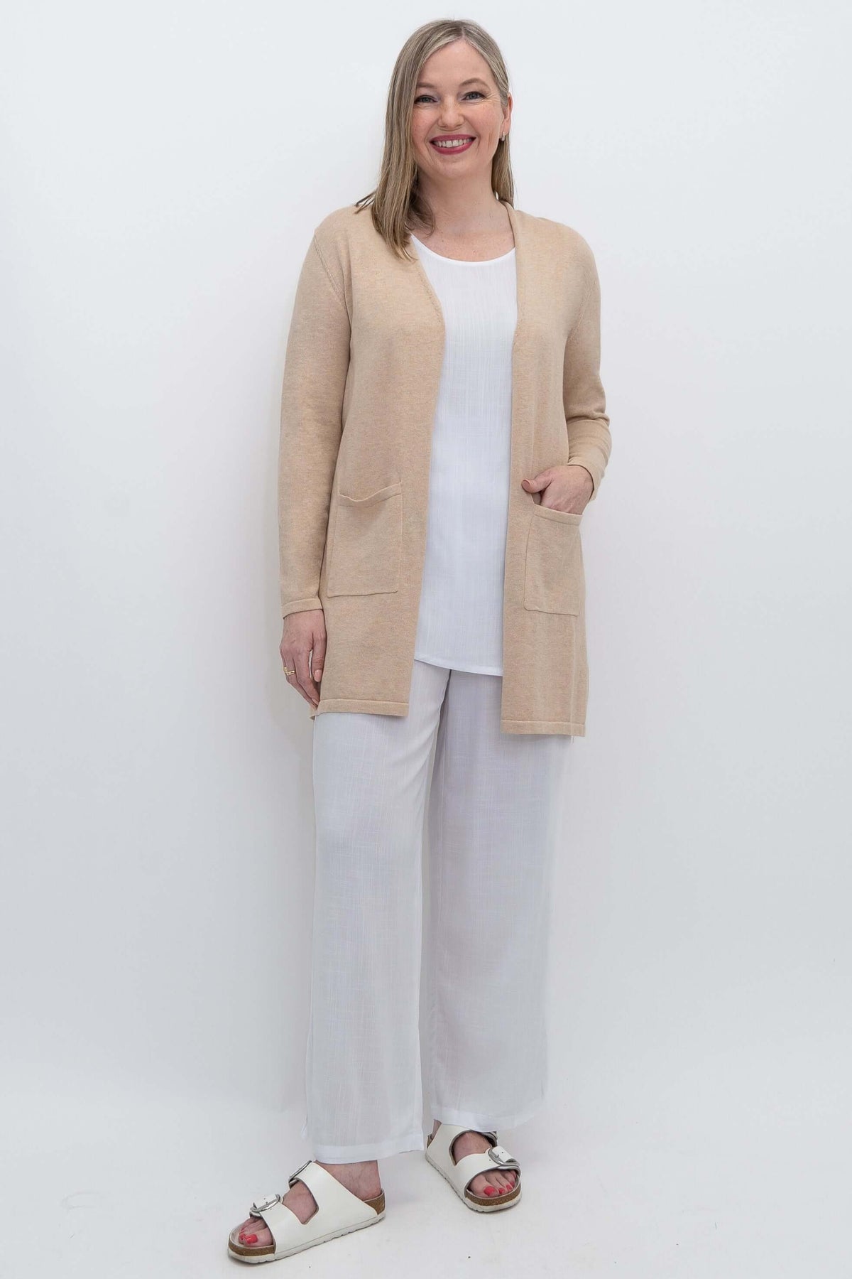 Full body view of woman in beige open cardigan and white outfit