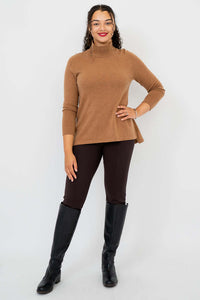 Full length view of woman in camel mock neck sweater, black pants, and boots