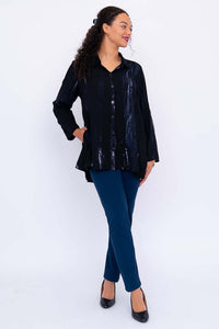 Full body view of model in black flowy tunic top paired with blue pants and black heels