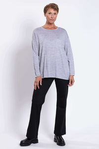 Full body view of woman modeling a light grey Merino wool sweater with black pants