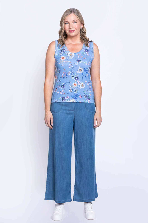 Full view of woman in blue floral tank top and wide-leg jeans, facing forward