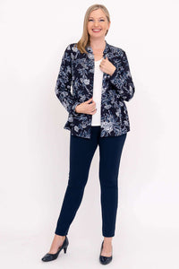 Full body view of model in navy floral top, open over a white shirt and navy pants