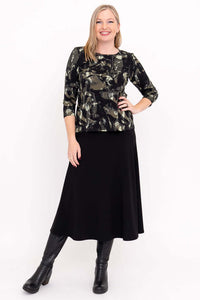 Full outfit view of woman in olive and black print tee with black skirt and boots