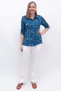 Woman modeling the blue floral blouse paired with white pants, full front view