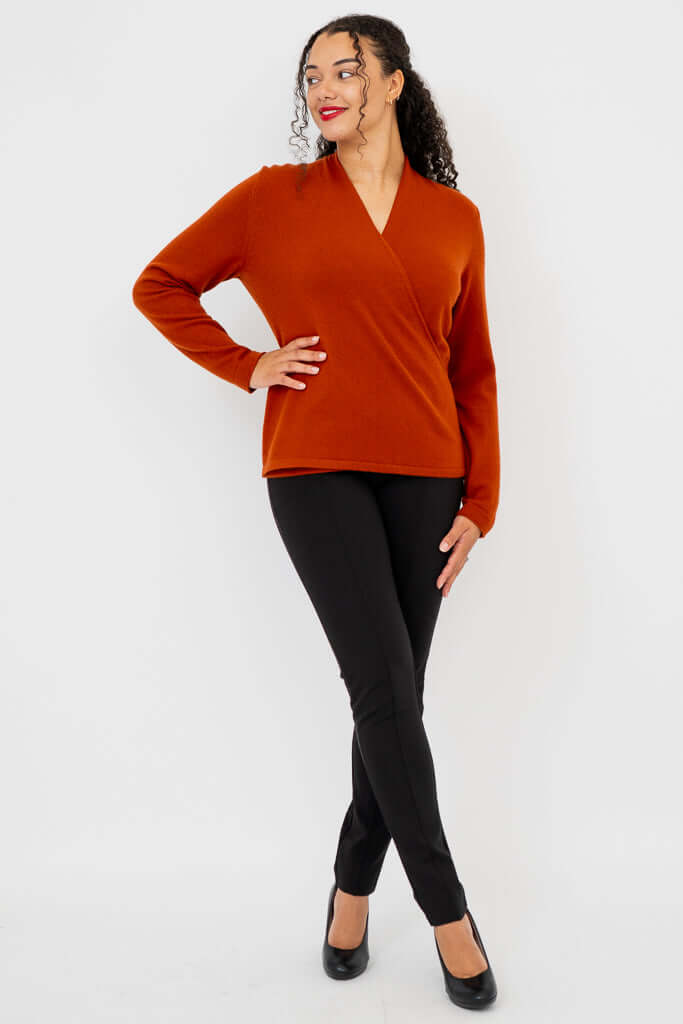 Woman posing in full outfit featuring rust cashmere sweater and black pants