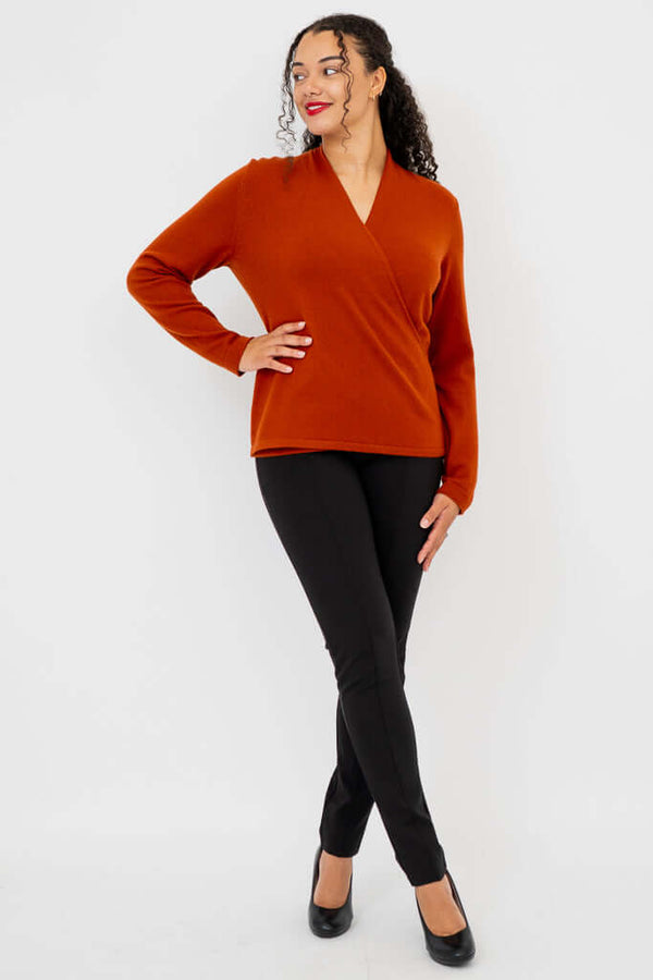 Woman posing in full outfit featuring rust cashmere sweater and black pants