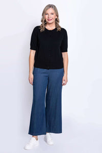 Full body view of woman in black short-sleeve cardigan and wide-leg blue pants