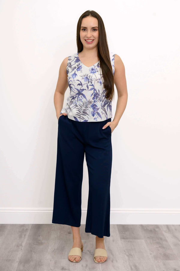 Model posing in full outfit, featuring a blue botanical cropped tank top and navy pants