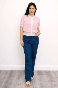 Full-length image of a woman in a pink pearl button cardigan, blue jeans, and beige sandals