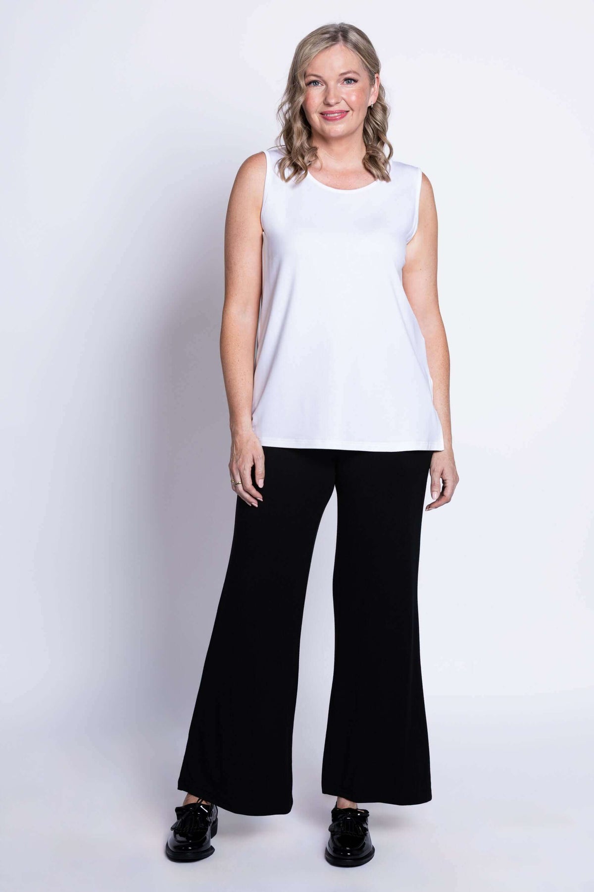 Full body shot of model in white sleeveless tank top and black pants