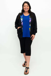 Woman in black zip hoody with floral lining and blue top, standing full-length