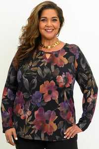 Smiling woman wearing a colorful magenta floral knit top with a keyhole notch neckline and long sleeves.