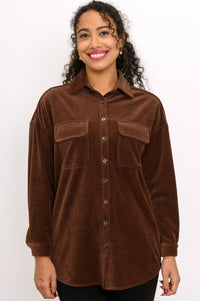 Front view of a smiling woman wearing a dark brown button-up corduroy shirt jacket with double flap pockets