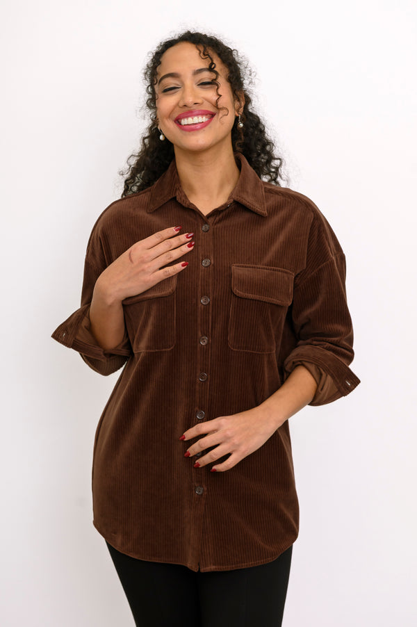 Front view of female model wearing a relaxed-fit brown cotton corduroy button-up jacket against white backdrop