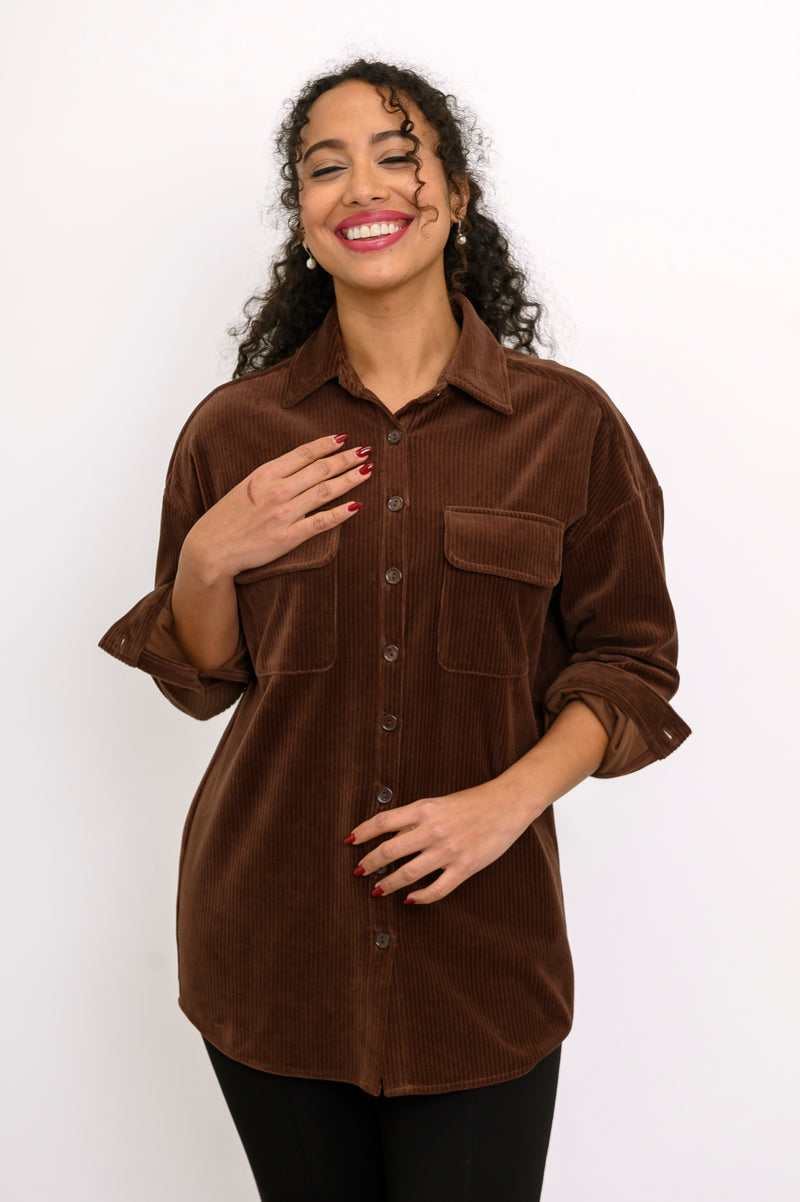 Front view of female model wearing a relaxed-fit brown cotton corduroy button-up jacket against white backdrop