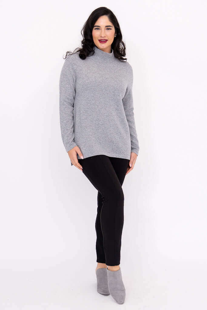 Woman posing in a grey cashmere wool sweater and black leggings with grey booties