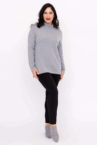 Woman posing in a grey cashmere wool sweater and black leggings with grey booties