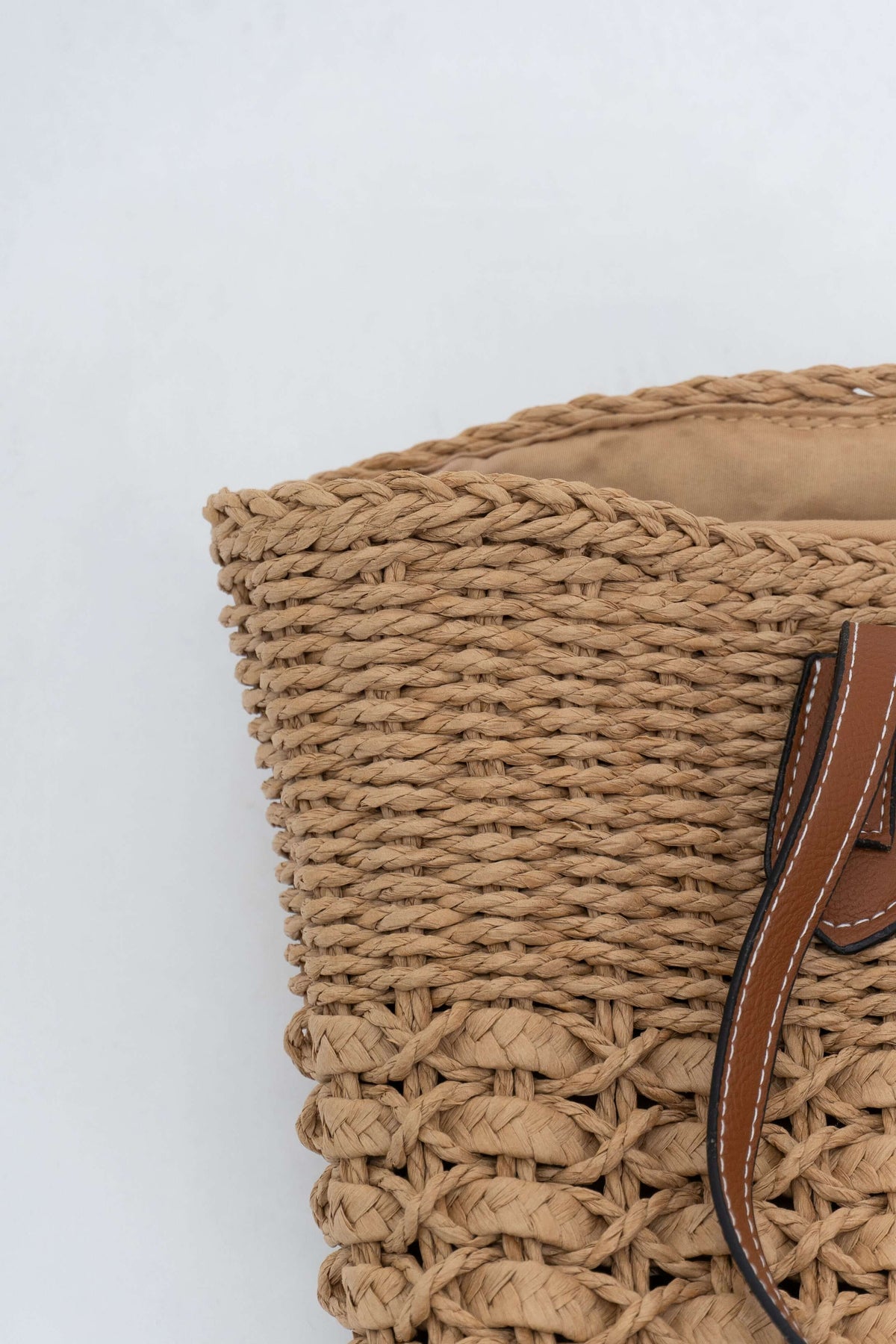 Detail of the woven texture and handle attachment on the left side of the tote bag