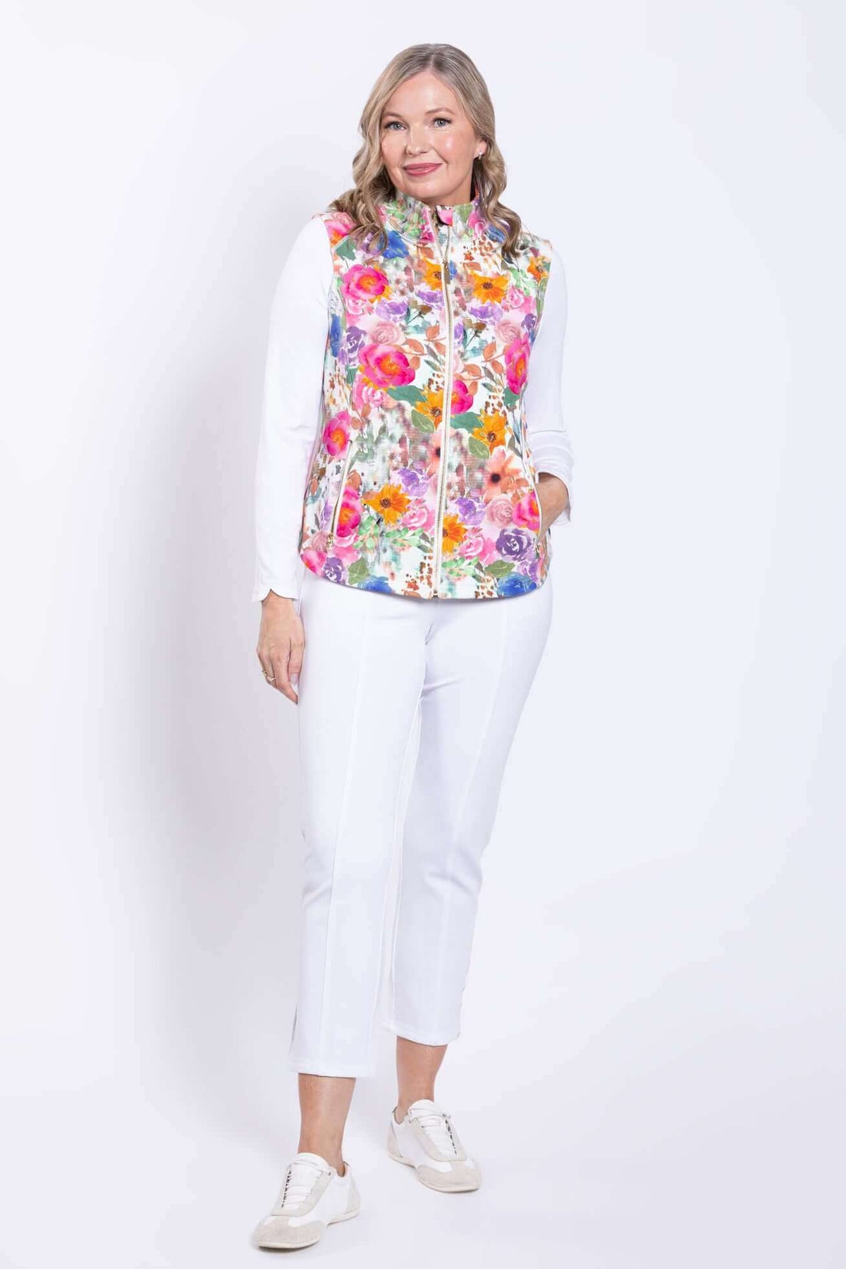 Woman modeling a pink floral print vest and white pants, facing forward