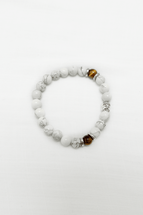 White howlite and tiger's eye beaded bracelet with silver Buddha charm on white fabric