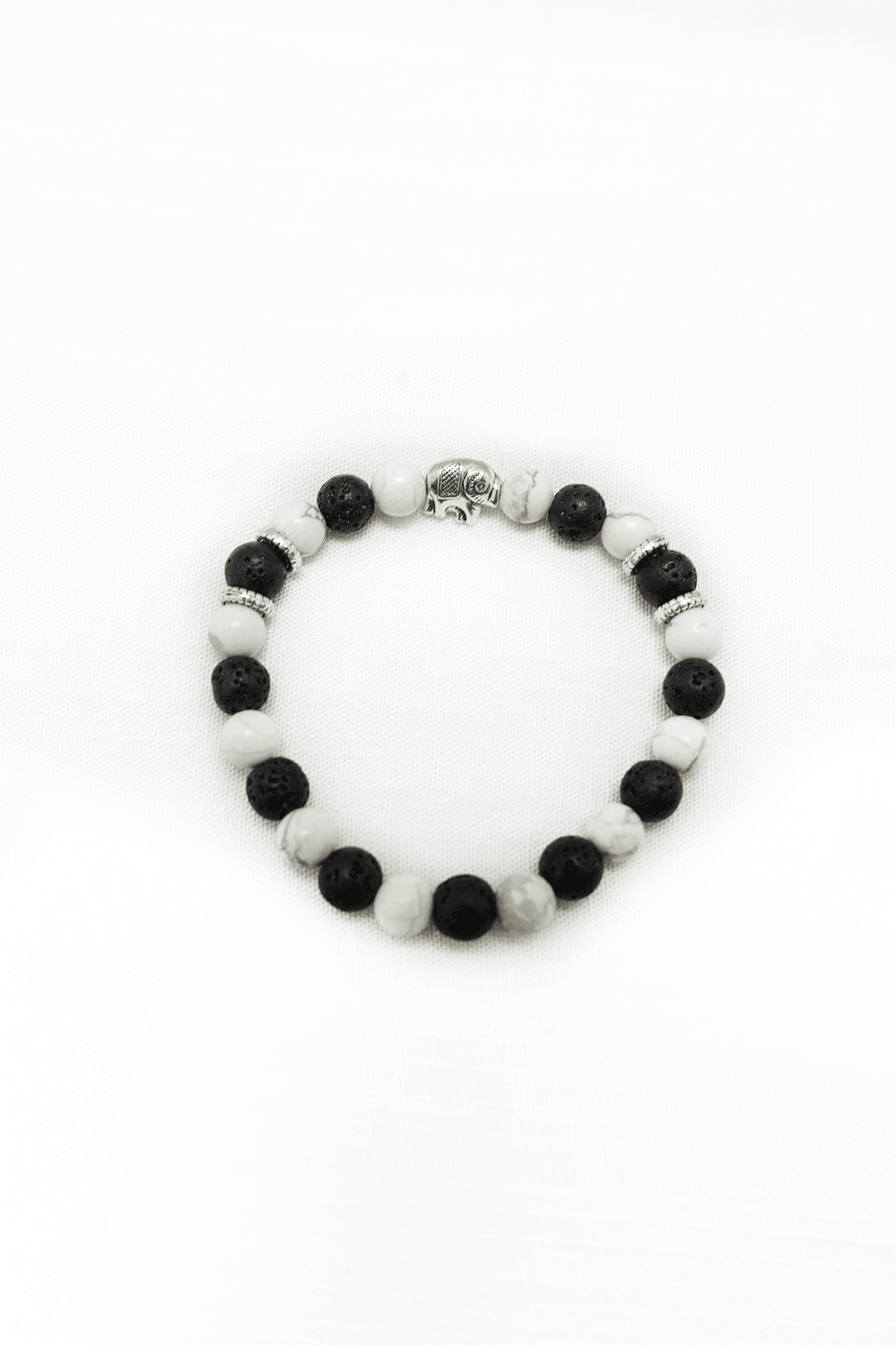 Howlite and lava stone beaded bracelet with silver accent and elephant charm on a white background