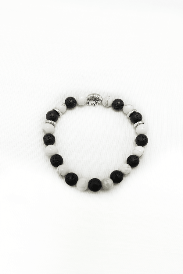 Howlite and lava stone beaded bracelet with silver accent and elephant charm on a white background