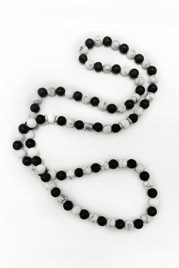 Howlite and lava stone meditation mala necklace with silver accent beads on a white background