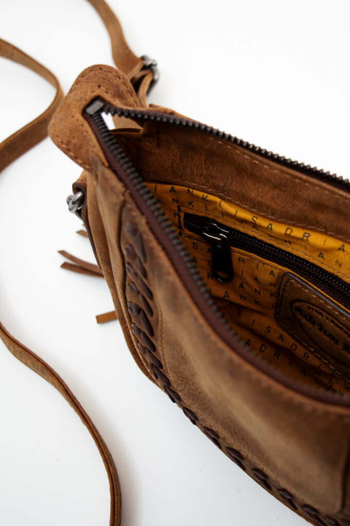 Close-up of open crossbody bag revealing patterned interior lining and zip pocket