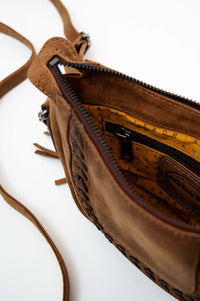 Close-up of open crossbody bag revealing patterned interior lining and zip pocket