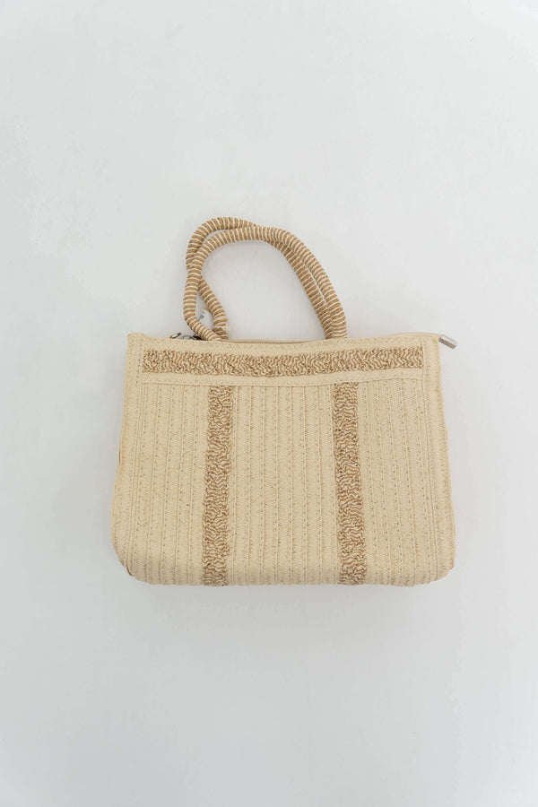 Flat lay of an ivory woven paper tote bag with double handles