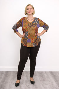 Model wearing a yellow and brown patterned V-neck bamboo tunic and brown pants, standing against a white wall.