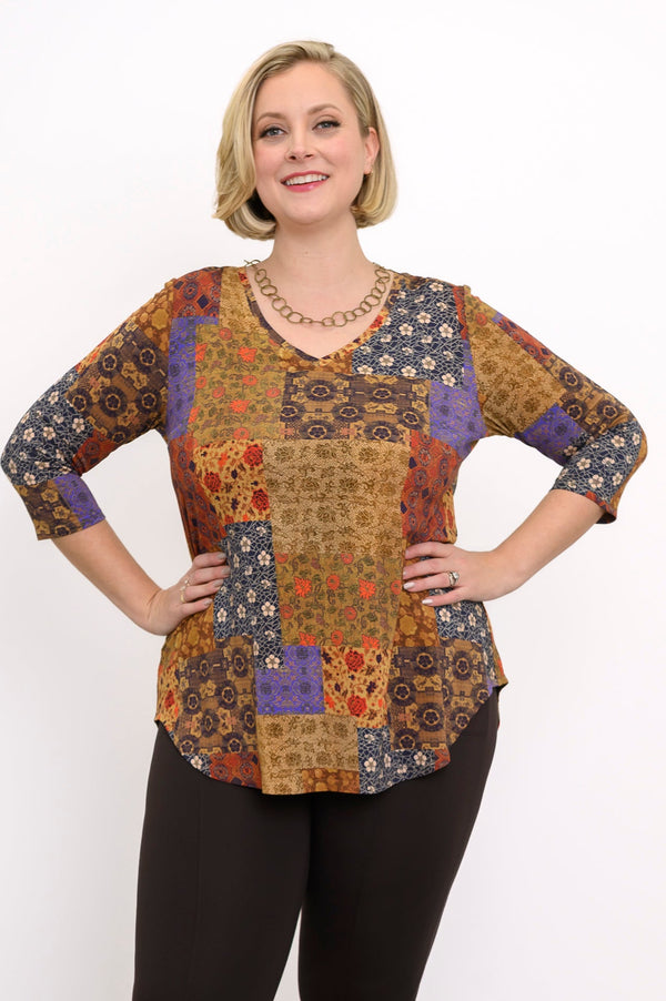 Model wearing a yellow and brown patterned V-neck bamboo tunic and brown pants, standing against a white wall.