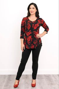 Model posing in a black and red floral print A-line tunic paired with fitted black pants, standing front-facing.