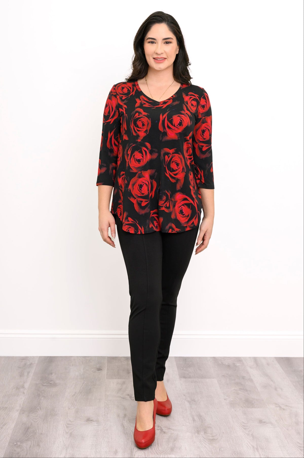 Women's three-quarter sleeve knit tunic in a dark rose pattern, paired with black trousers in a relaxed pose.