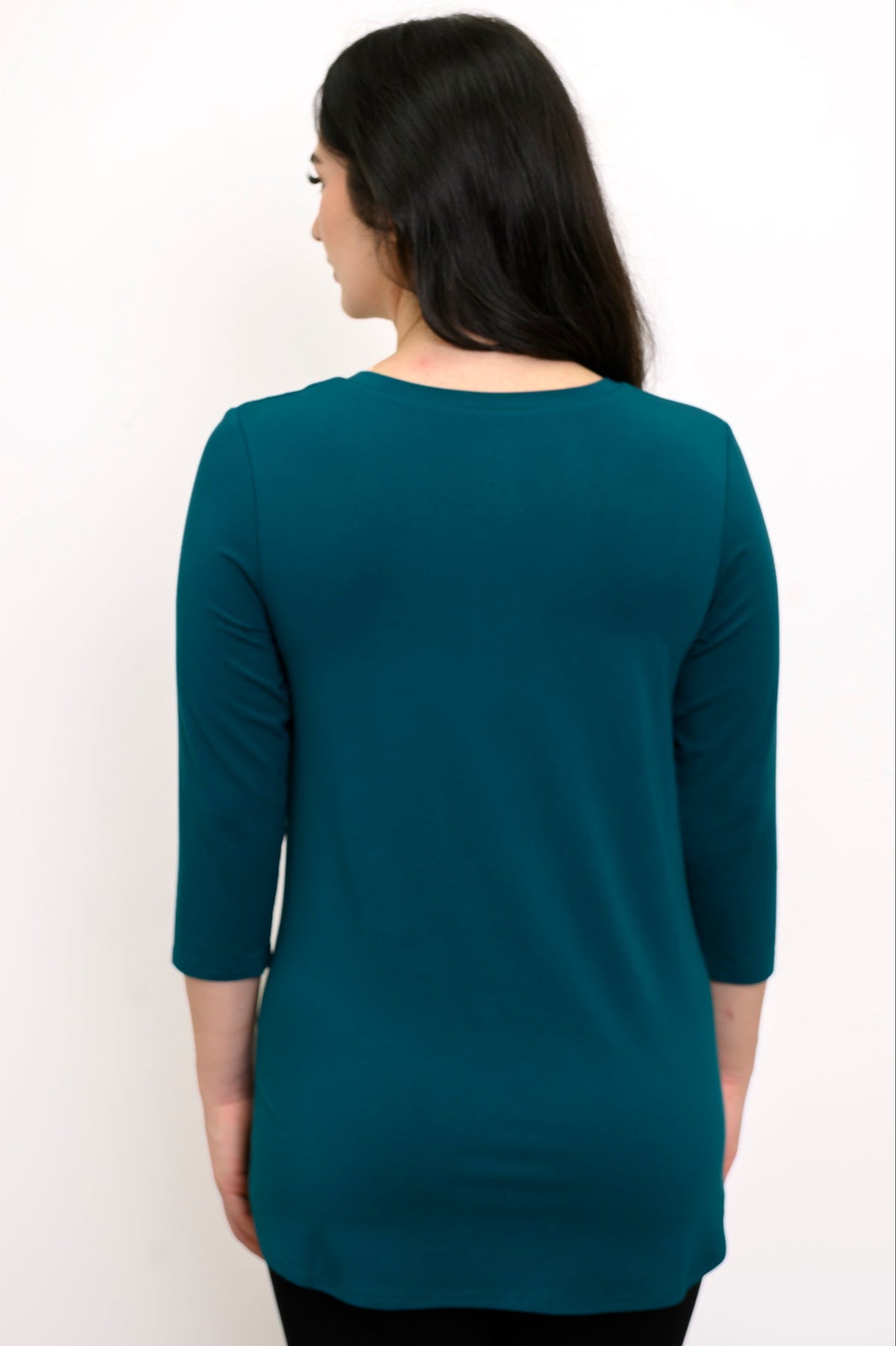Back view of model wearing a 3/4 sleeve teal colored shirt against a white background