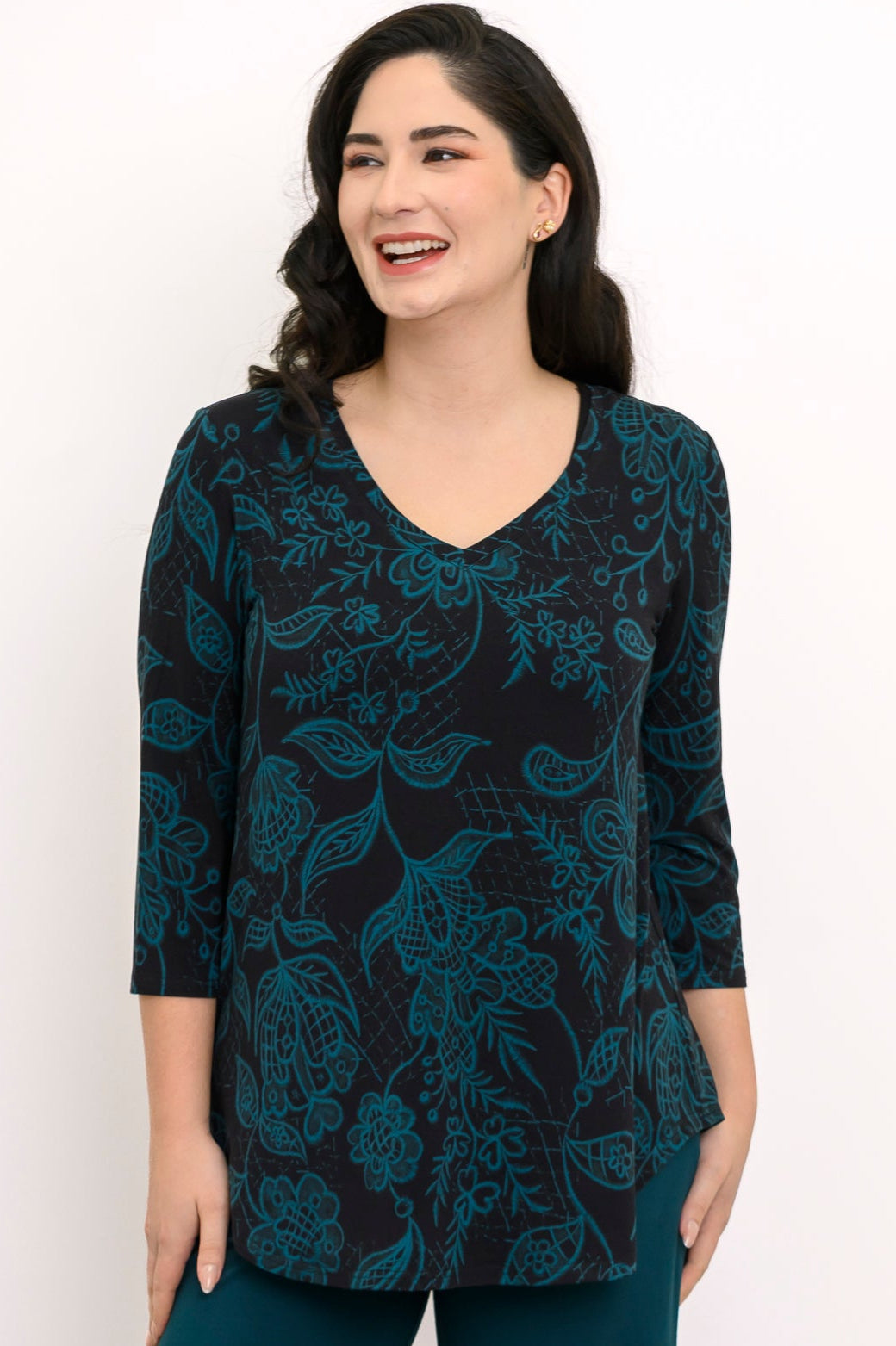 Smiling woman wearing a teal botanical print bamboo V-neck top with 3/4 sleeves, shown in a front-facing view.