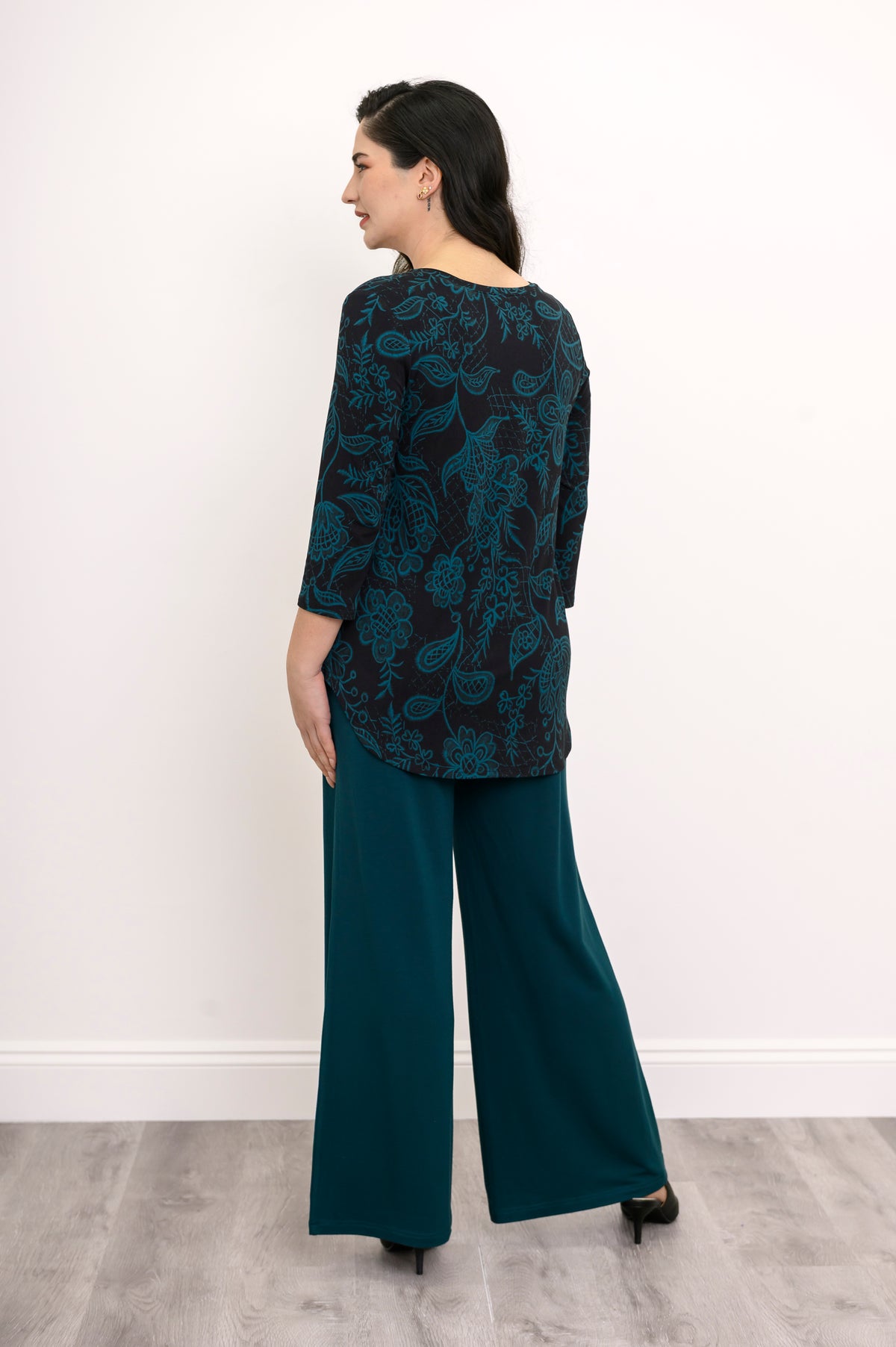 Rear view of a coordinating teal leaf print knit set, highlighting the straight back hem of the 3/4 sleeve top.