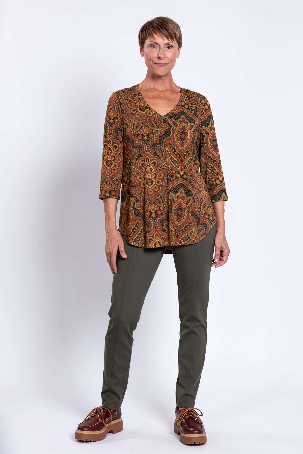 Full front pose of woman in Jackie V-neck bamboo top, green pants, and brown shoes
