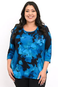 Close-up of a smiling woman wearing a blue and black floral print bamboo top with a scoop neckline.