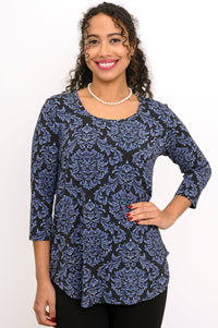 Front view of a smiling woman wearing a blue patterned rounded hem top with 3/4 sleeves and a scoop neckline.