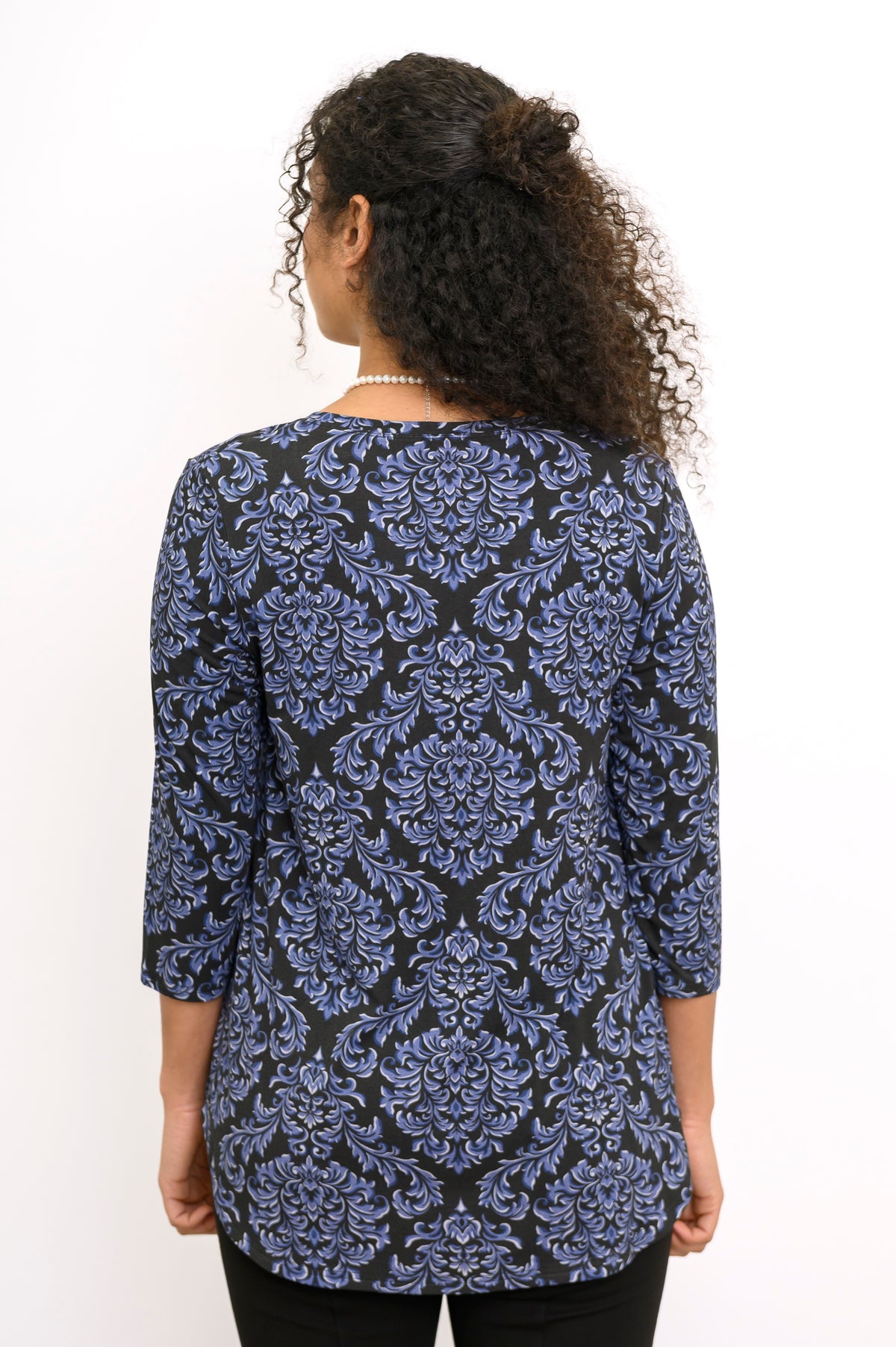Back view of a woman wearing an indigo patterned 3/4 sleeve bamboo top with a clean shoulder fit.