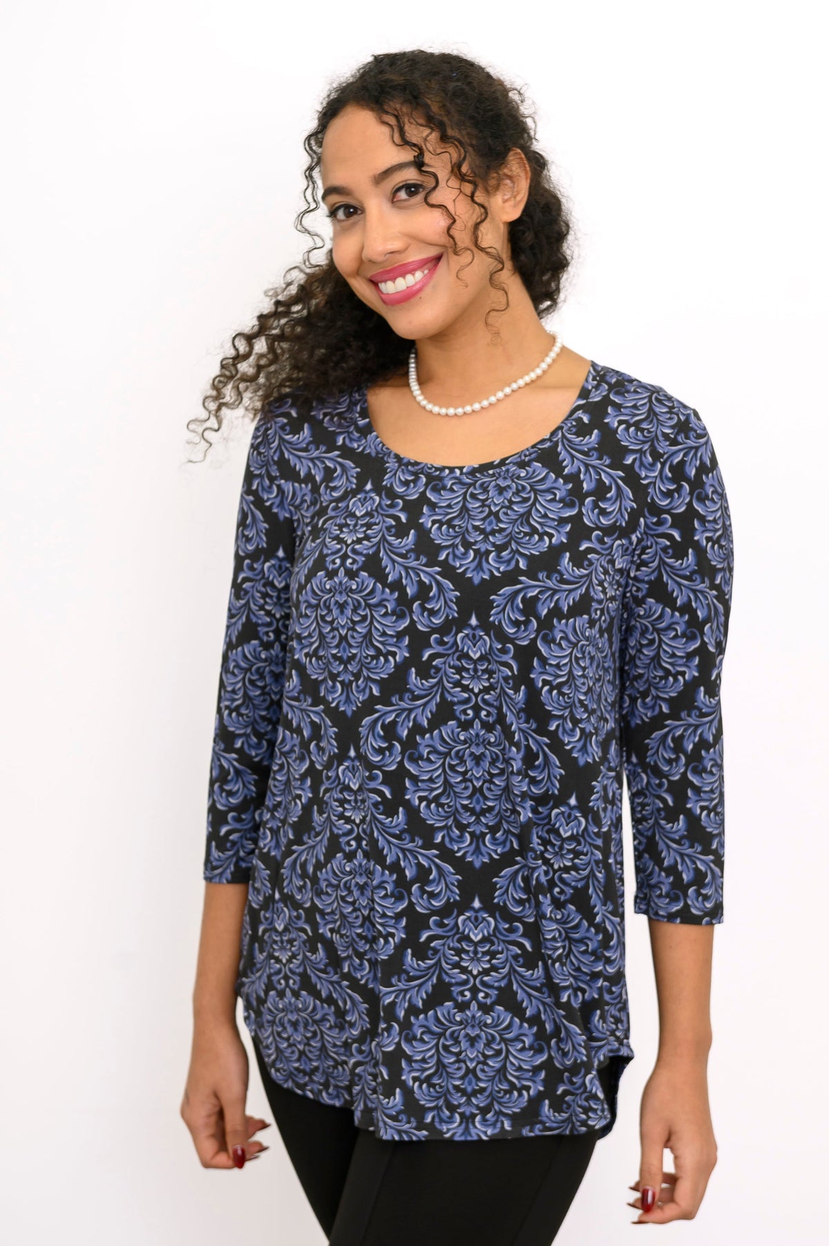 Angled view of a women's blue floral print 3/4 sleeve top showing the generous fit at the midsection.