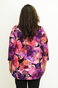 Back view of a women's patterned pink bamboo-cotton top, styled with black pants on a plain background.