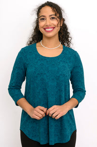 A-line patterned teal knit blouse with three-quarter sleeves and a round neckline, styled with black pants.