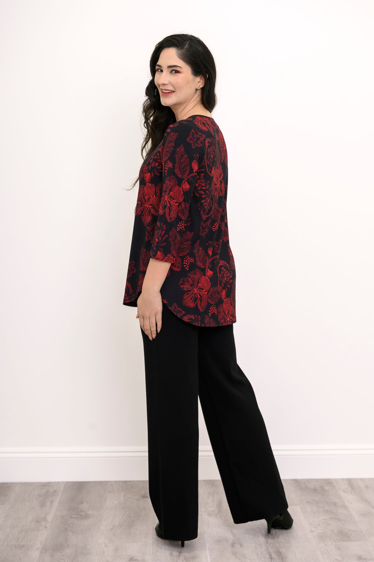 Back view of a red and black floral print bamboo top, illustrating a loose, hip-covering length and rounded hem.