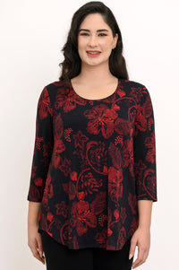 Smiling woman wearing a black knit top with a red abstract floral print, featuring a scoop neck and 3/4 sleeves.